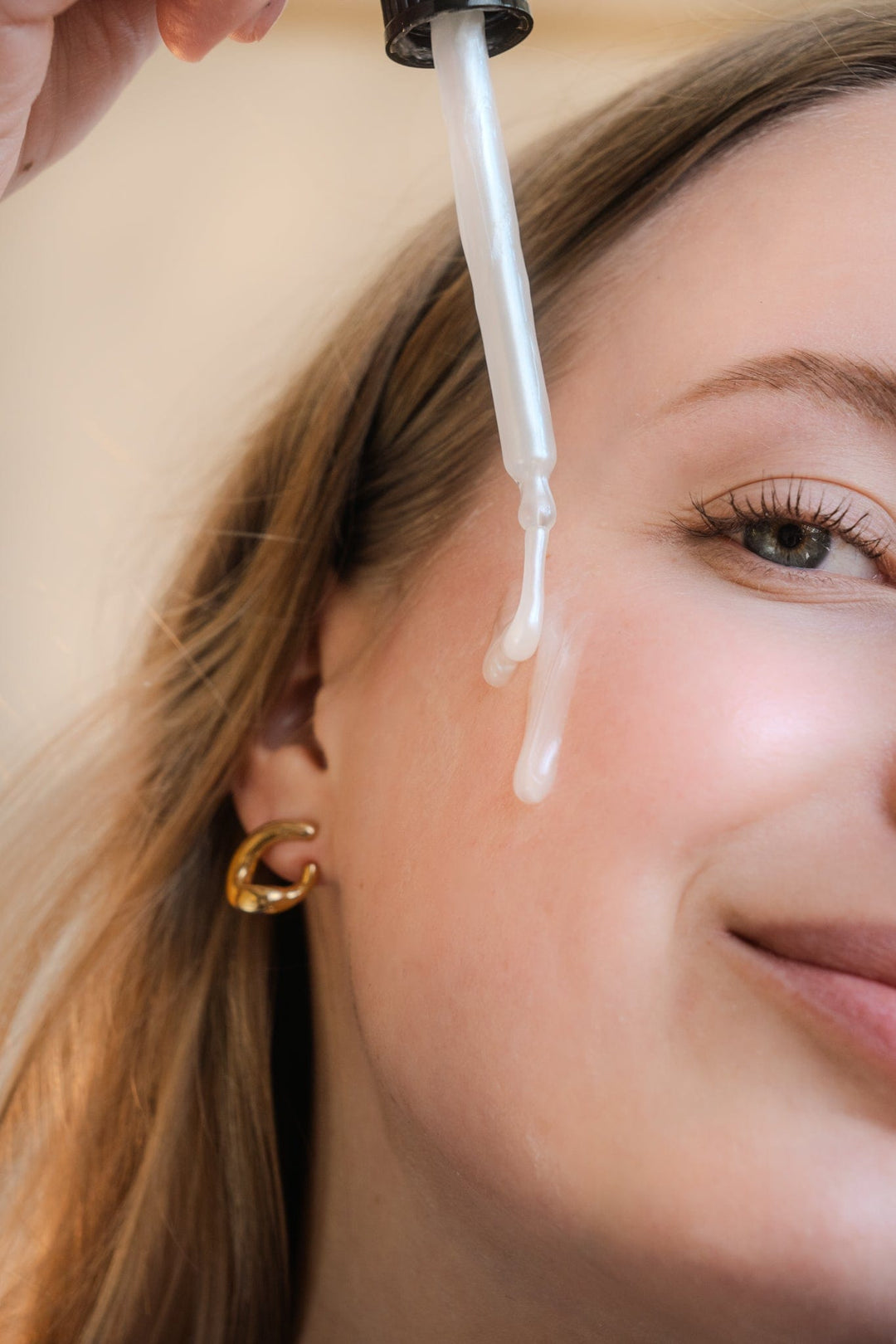 Frau mit Pipette und Glow Hydtrator Serum im Gesicht